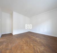 A spacious room with white walls and a wood-decorated floor in a 3-room apartment.