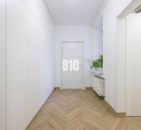 A cozy hallway with white walls, a wooden decor floor, and a plant in a 3-room apartment.