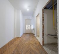 A hallway in a 3-room apartment with a wooden decor floor and piping in the wall.