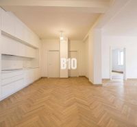 Interior of a 3-room apartment with a white kitchen and a floor with a wood decor.