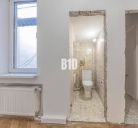 Bathroom with ceramic tiles and a window, next to it a floor with a wood decor.