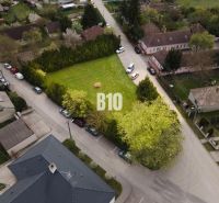 Residential plots in Kráľovičove Kračany with greenery and surrounding houses.