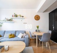 Living room with a gray sofa, round table, and wood-patterned flooring in a two-room apartment.