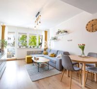 Interior of a 2-room apartment with wood-patterned flooring, a sofa, and a dining area.