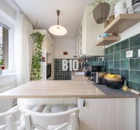 A kitchen in a 2-room apartment with a kitchen unit, wooden decor, and green tiles.
