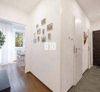 A hallway in a 2-room apartment with a wood-patterned floor and white walls.