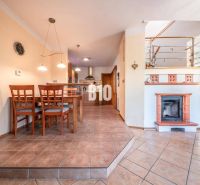 Dining room with a fireplace and kitchen in a family house with ceramic tiles.