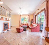 Living room in a family house with a fireplace, red sofa, and windows with a view.