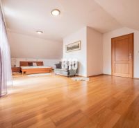 Spacious bright room, wooden floor, bed and chair, family house.