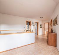 A hallway with ceramic tiles, wooden railing, and a wardrobe in a family house.