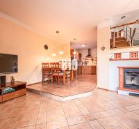 Living room of a family house with a fireplace, dining table, and kitchen with tiles.