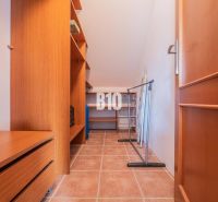 A wardrobe in a family house with cabinets, shelves, and a tiled floor.