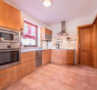 A kitchen in a family house with a tiled floor, wooden decor, and stainless steel appliances.