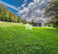 A family house in Marianka with a garden and a forest backdrop under a blue sky.