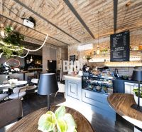 A café with a brick ceiling, modern lighting, and a bar, with a wooden decor floor.