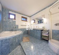 A bathroom in a family house with a bathtub, a shower corner, and blue ceramic tiles.
