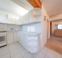 A kitchen in a family house with white kitchen cabinets and a tiled floor.