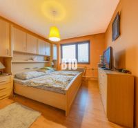 A bedroom in a family house with orange walls and a wood-patterned floor.