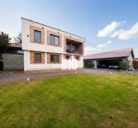 A family house in Štvrtok na Ostrove with a garage, grassy plot, and brick facade decor.