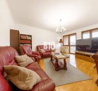 Living room in a family house with a leather sofa, bookshelf, and wooden decor flooring.
