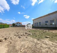 A plot of land with a view of a family house in Kalinkovo, bordered by fences, blue sky.