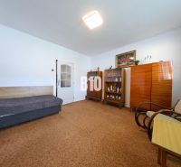 A room in a family house with a sofa, cabinets, and an armchair on a carpet.