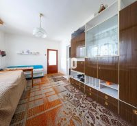 Interior of a family house with a sofa, cabinet, and dining table, carpet on the floor.