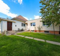 A family house in Kalinkovo with a well-maintained garden and two entrances under the blue sky.
