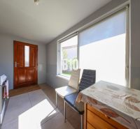 A kitchen in a family house with sunny windows and a wooden table.