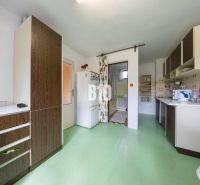 A kitchen in a family house with a green floor and wooden decor on the cabinets.