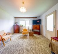 A living room in a family house with carpeted flooring and simple furniture.