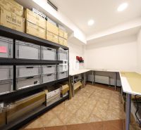 Warehouse spaces with shelving systems and folding tables.