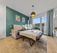 Bright living room with a sofa bed and access to the balcony in a studio apartment.