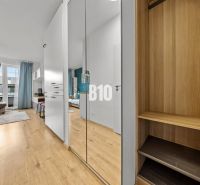 In a one-room apartment with a wooden decor floor, there are mirrored wardrobes and a balcony.