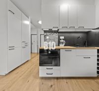 A kitchen with white cabinets, a black countertop, and a wood-patterned floor.