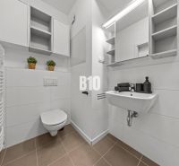 A bathroom in a studio apartment with white sanitary ware and storage spaces.
