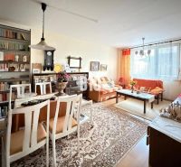 Living room with a dining table and shelves in a three-room apartment with a wooden decor floor.