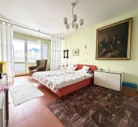 A room with a double bed, a painting on the wall, and a floor with a wooden decor.