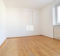 A bright room with a wood-patterned floor and a large window in a family house.