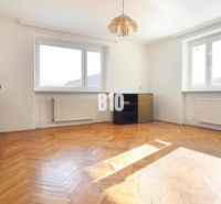 Living room with wood-patterned flooring and a glass display cabinet in a family house.