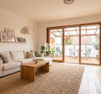 A living room in a family house with a light sofa, a wooden table, and a spacious terrace.