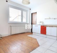 A kitchen in a family house with a wooden decor floor and white tiles.