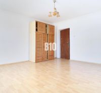 A spacious room with a wooden decor floor and a cabinet in a family house.