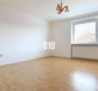 An empty room in a family house with a wood-patterned floor and a large window.