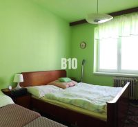 Green bedroom with two beds and furniture in a three-room apartment.