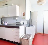 A kitchen in a 3-room apartment with white furniture and a red floor.
