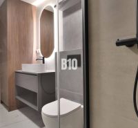 Bathroom in a 2-room apartment with a wooden decor floor and a shower corner.