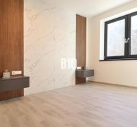 This room in a 2-room apartment has a floor with a wooden decor and a wall with a marble pattern.