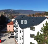 A new apartment building in Dolný Kubín, with a view of the mountains and a parking lot.