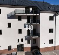 The facade of an apartment building in Dolný Kubín with a parking lot and balconies, ideal for a 2-room apartment.